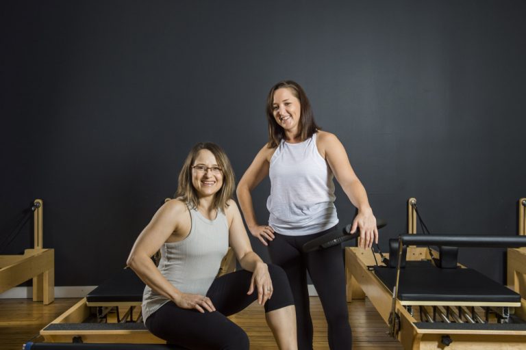 Cat and Anita from Movement Principle Pilates Brisbane smiling with reformer pilates equipment